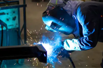 Welder working on a metal beam with sparks, representing metal fabrication and welding applications.