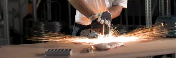 Person using a Stud welding gun with sparks bursting from weld