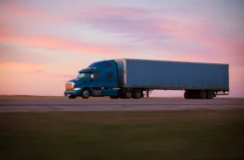 Semi-truck and trailer driving on the highway at sunset, representing trucking and trailer applications.